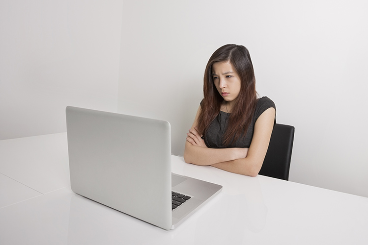 angry young woman looking at laptop