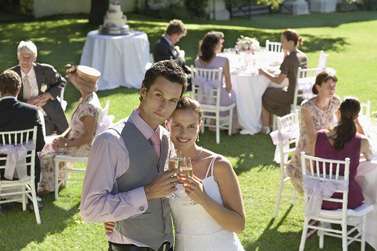 bride and groom in garden among wedding guests holding wineglasses