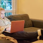 woman in warm robe using laptop at home in winter