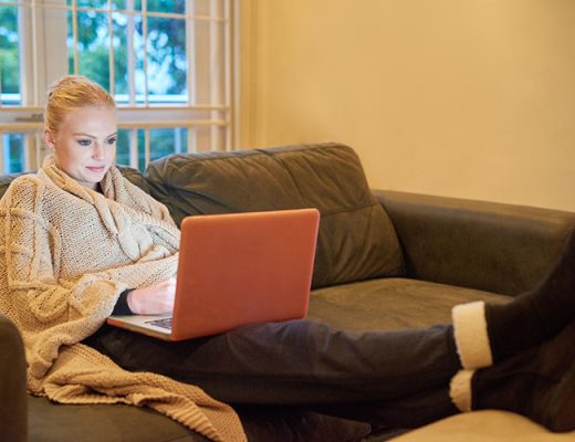 woman in warm robe using laptop at home in winter