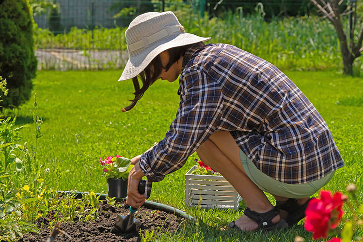 young girl in a straw hat is engaged in gardening work, planting flowers