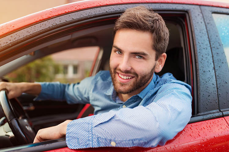 handsome young man in a blue shirt driving a car