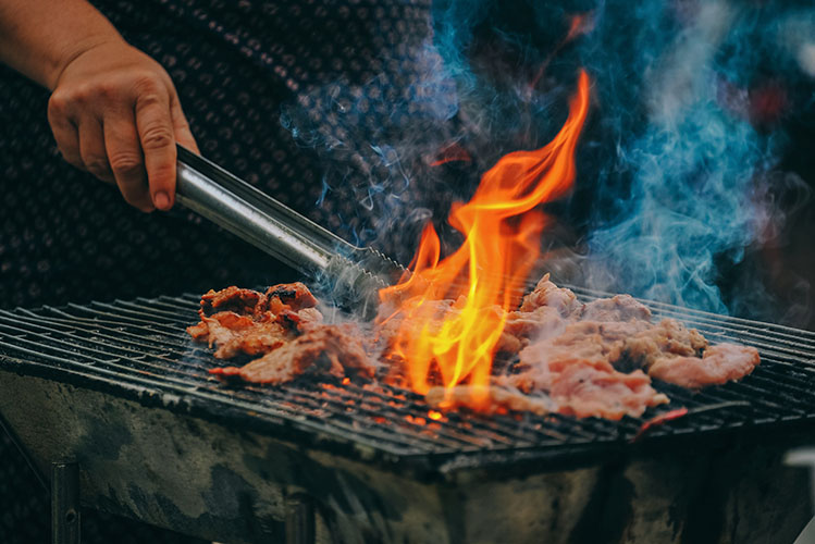 man cooking meat on grill