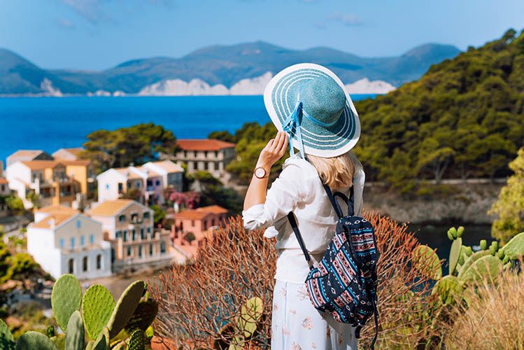 Tourist woman with blue sunhat, white clothes and travel backpack