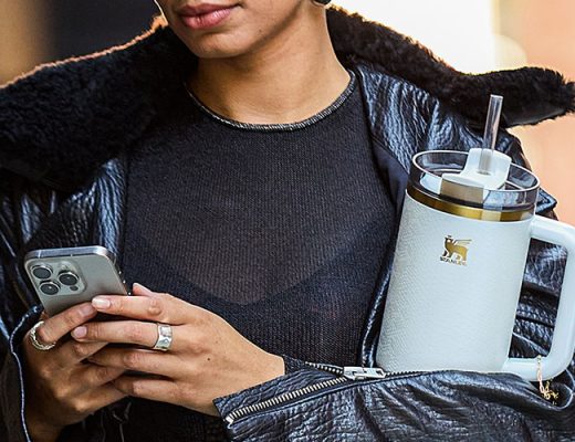 woman holding phone and travel mug