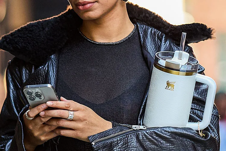 woman holding phone and travel mug
