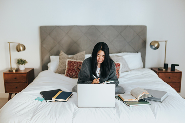 woman in bed working on laptop
