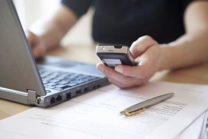 Woman using laptop and mobile phone