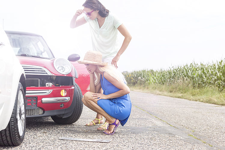 women looking at damaged cars on road