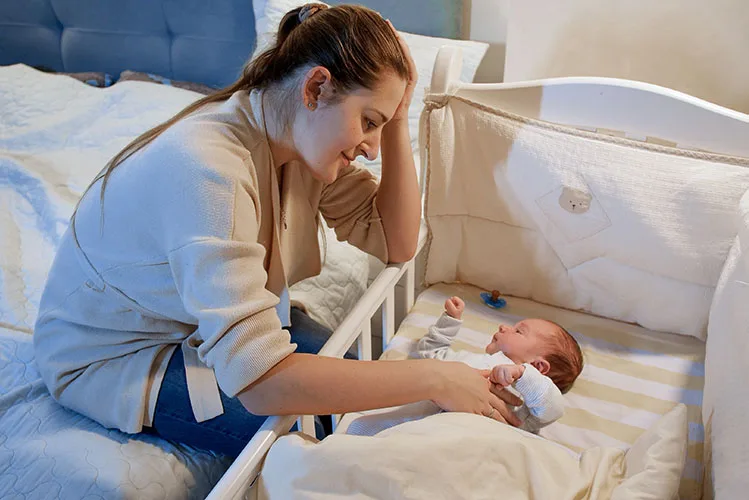 Young mother with her baby in crib