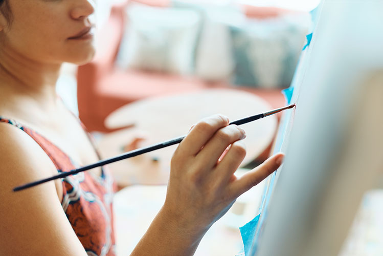young woman painting in her home studio